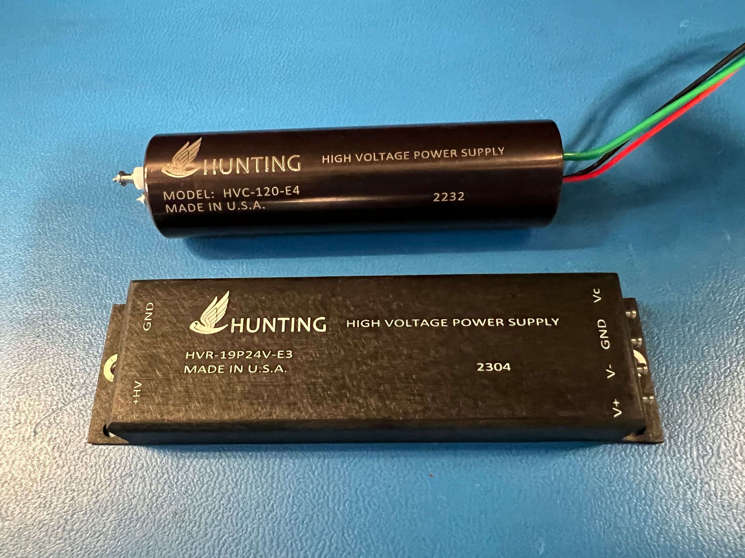 One tubular shaped and one flat box shaped power supply with cables coming out on one side