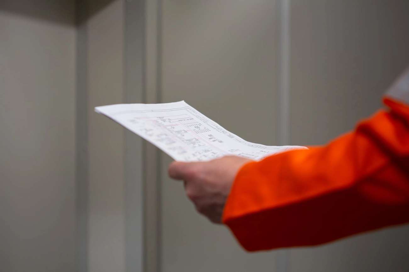 Person in orange boiler suit holding a plan