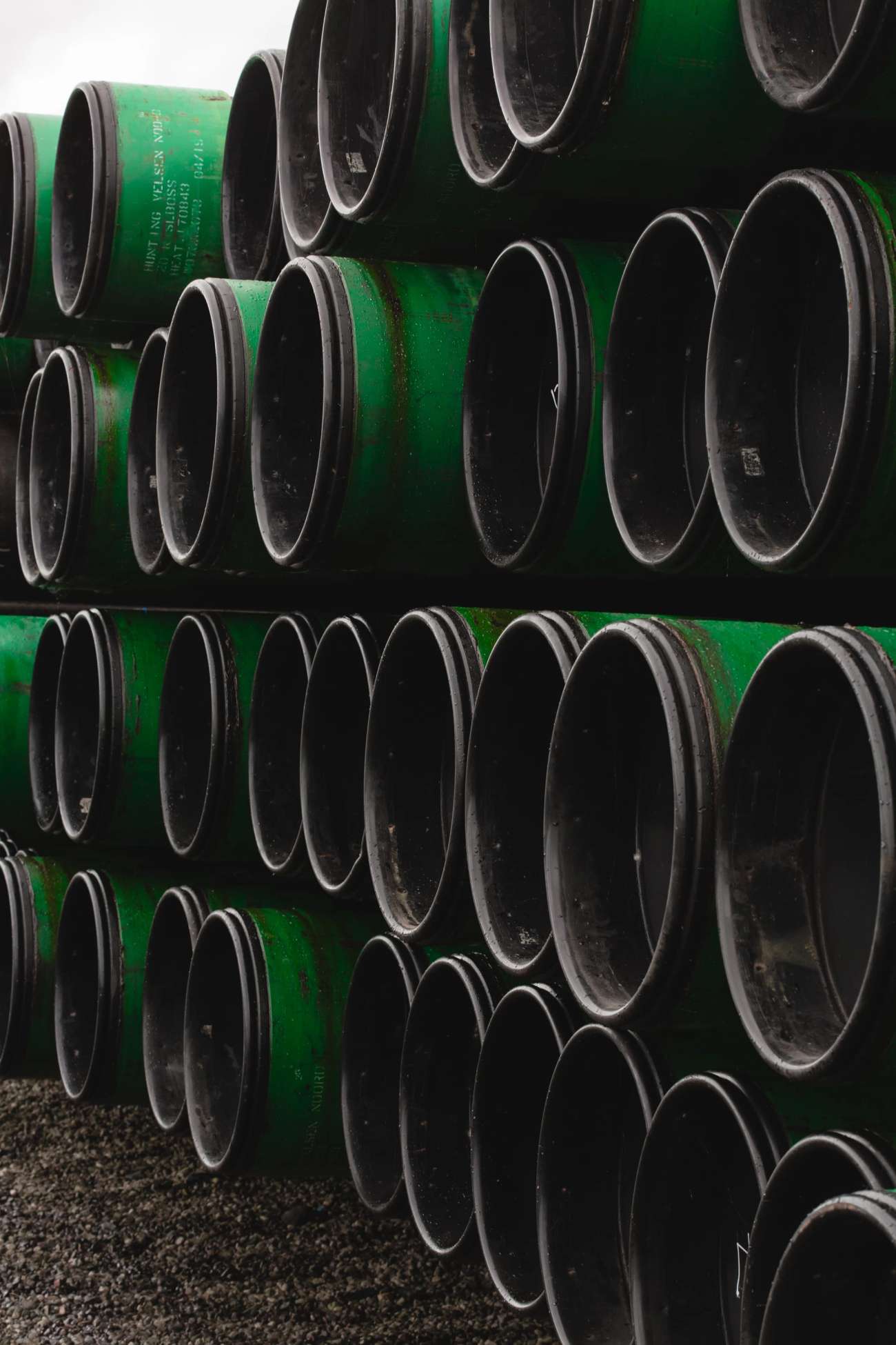 Green and grey pipes stacked in a yard