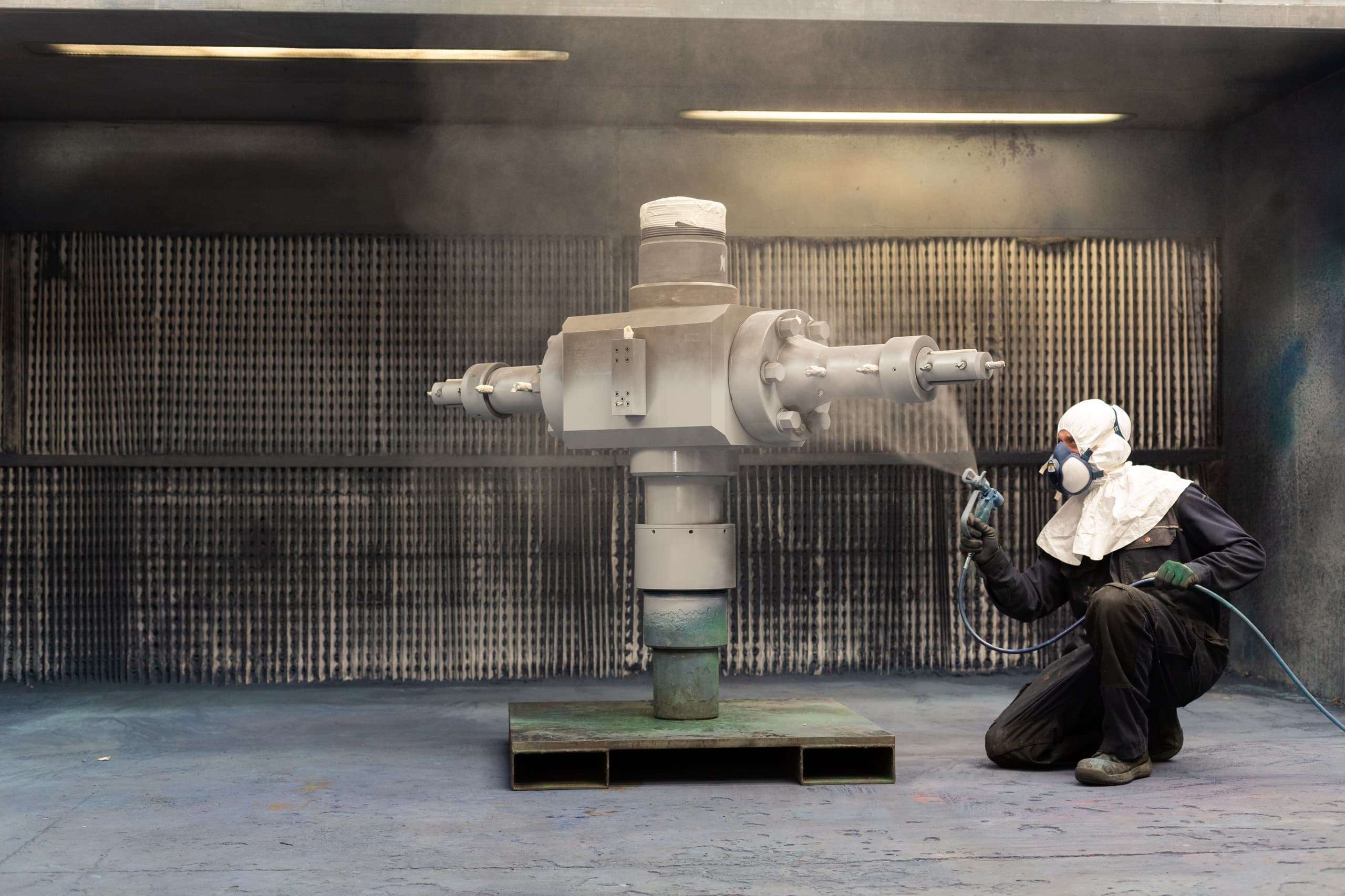 Person spray painting a machine part