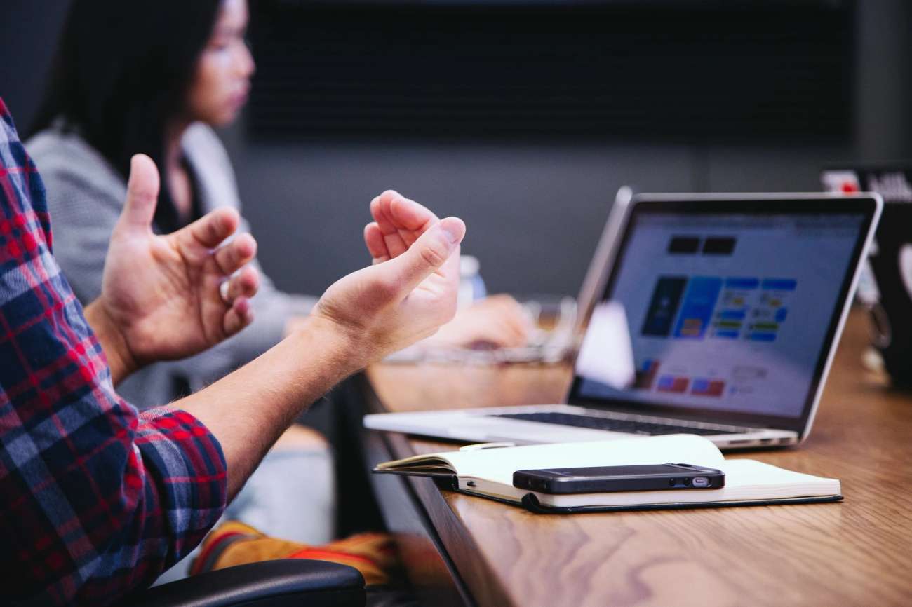 Hands of person at a meeting with notebook and laptop on a table