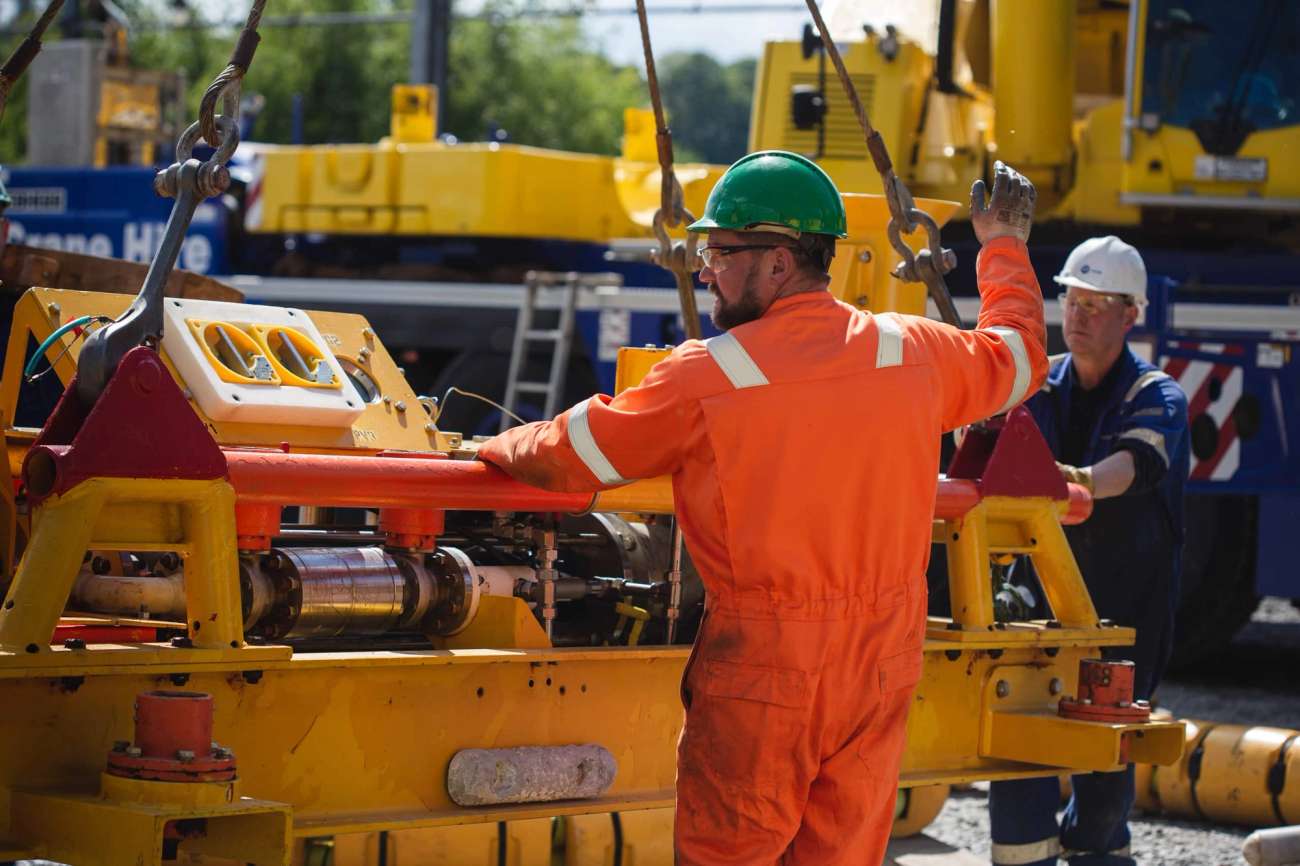 Person in boiler suit moving machinery in yard
