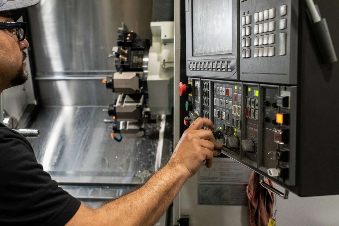 Person wearing a cap and safety glasses whilst operating a CNC machine 