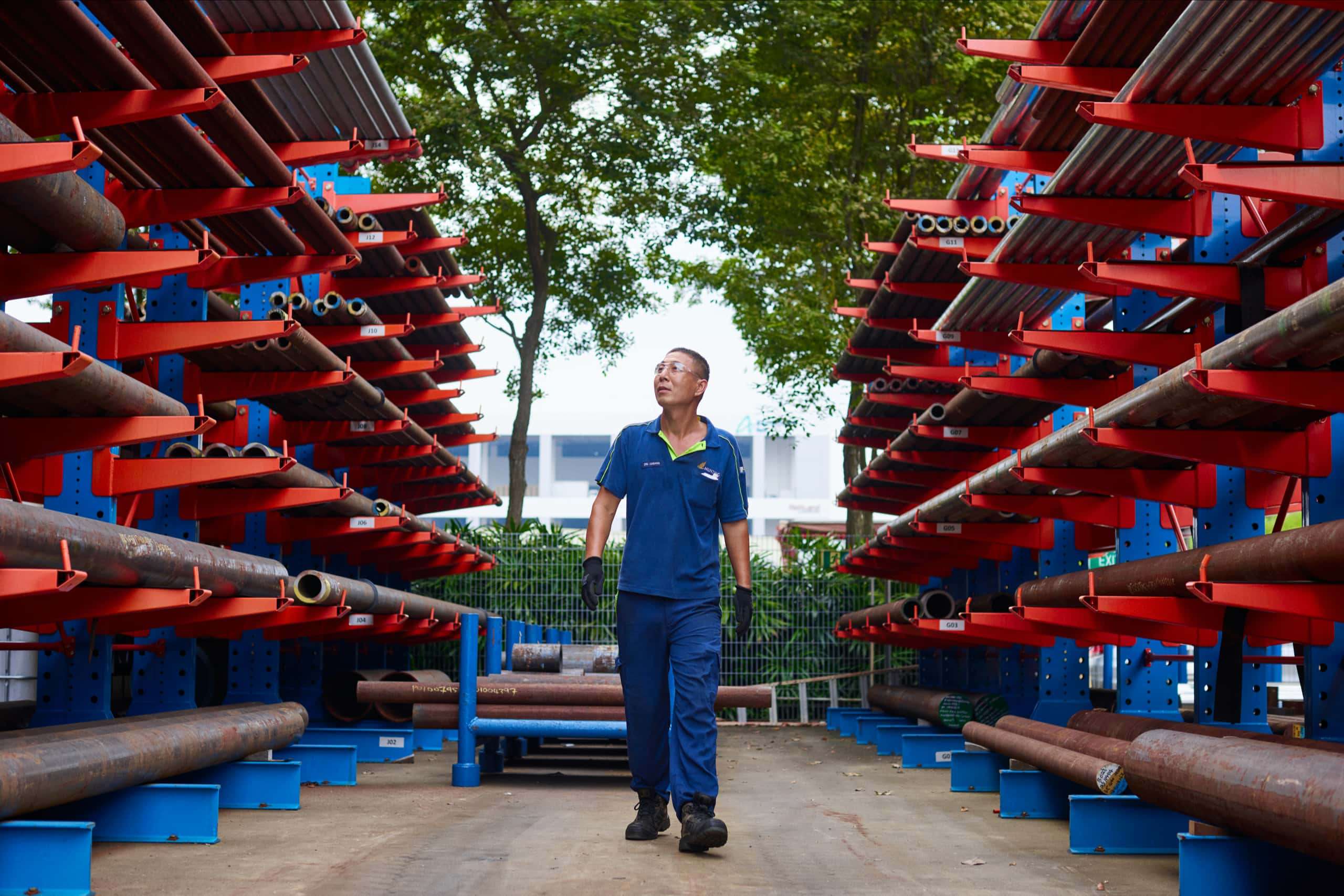 Man in blue Hunting outfit wearing protective goggles walking through a pipeyard
