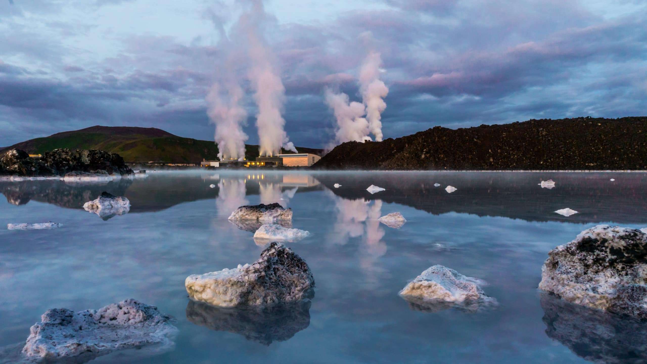 Still lake with smoking geothermal power plant in the background