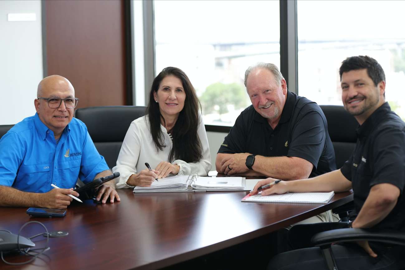 Four people sitting around a table smiling into the camera