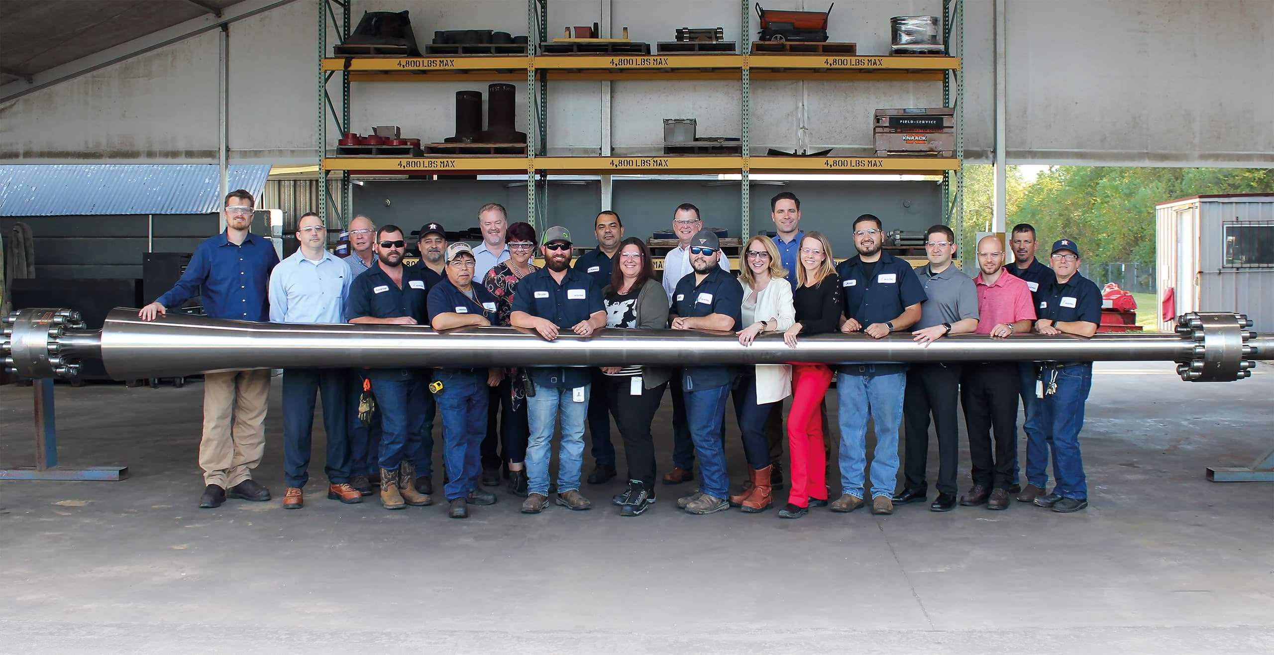 Group of people facing the camera leaning on a long metal tool