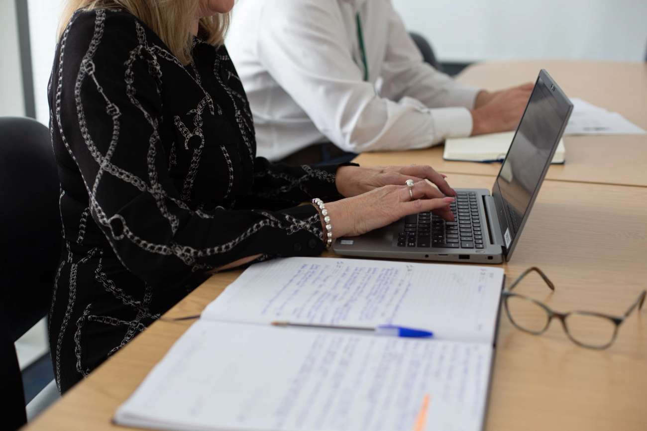 Person typing on laptop with open notebook on side