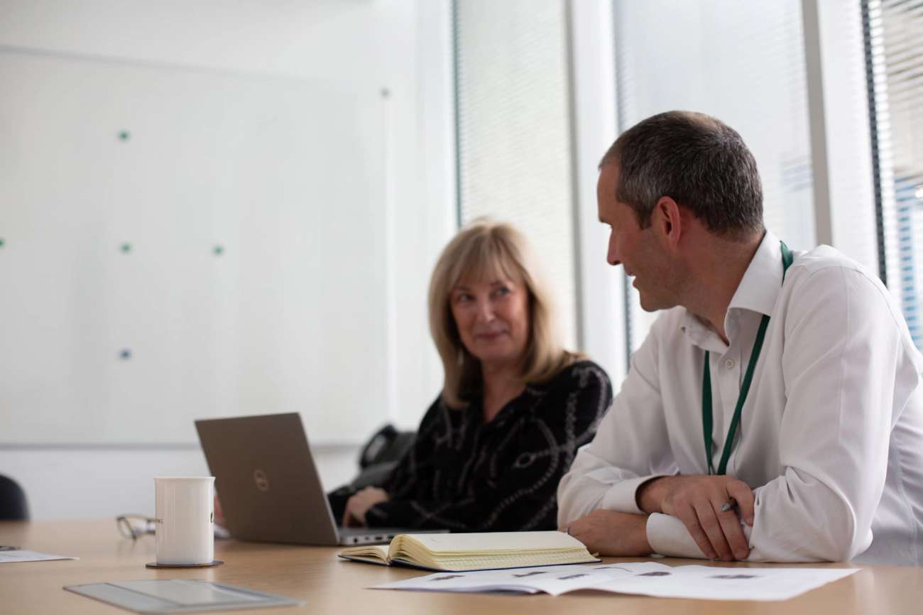 Two people sitting at a desk talking