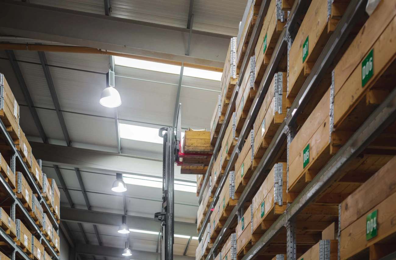Shelves in warehouse with wooden boxes and a forklift